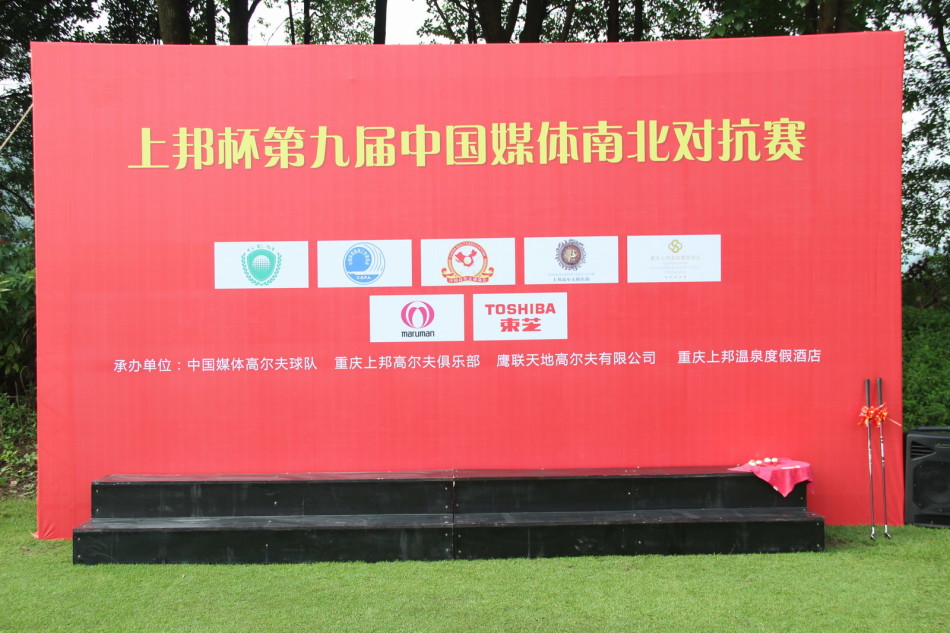 重庆上邦球场出发台前,队员们身着统一红色服装,精神抖擞地聆听赛前指导,背景是翠绿的球场与蔚蓝天空。