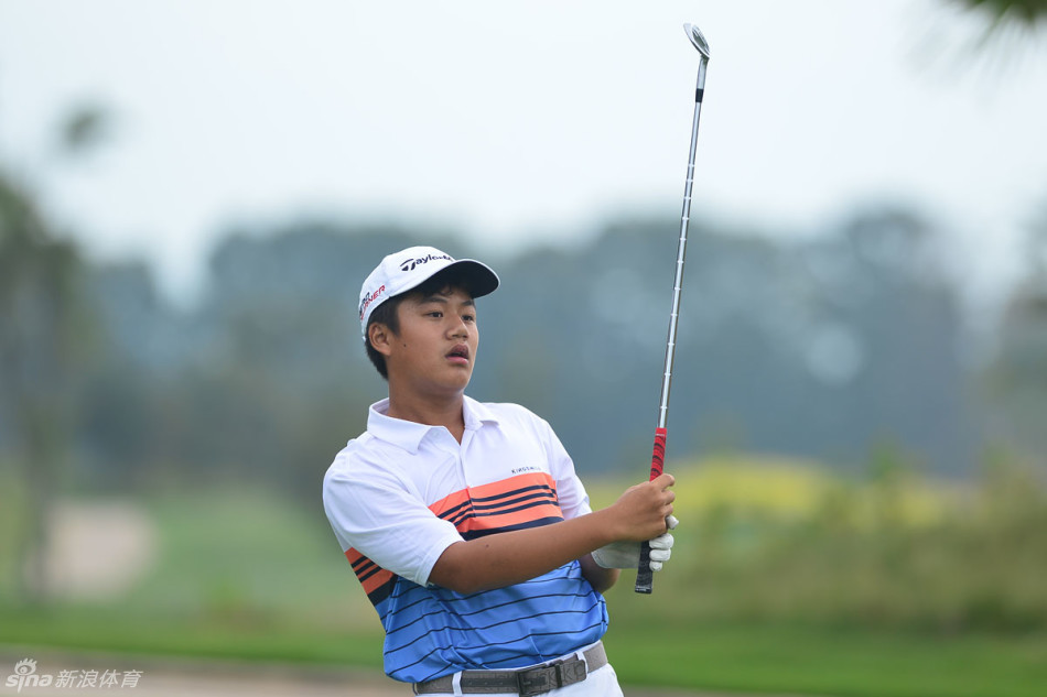 一位小球员正全力挥杆，脸上露出咬紧牙关、全力以赴的可爱表情