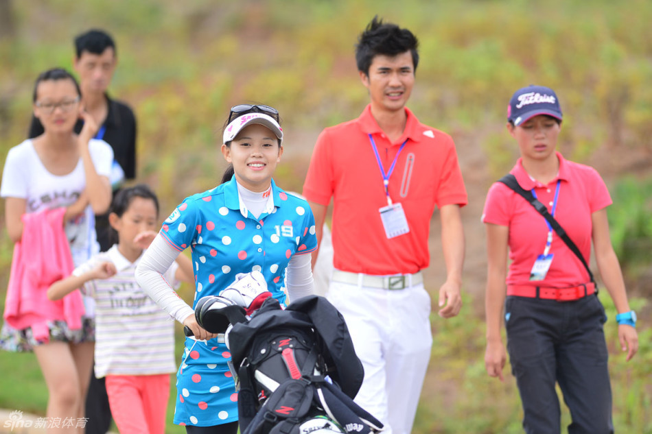 教练白翔瑞身着亮眼橙色上衣，正俯身细心指导一位小球员调整握杆手势