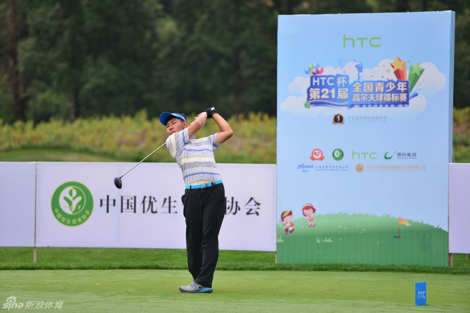 小球员在果岭上全神贯注地俯身观察推杆路线，一场专注与技巧的迷你对决在此上演