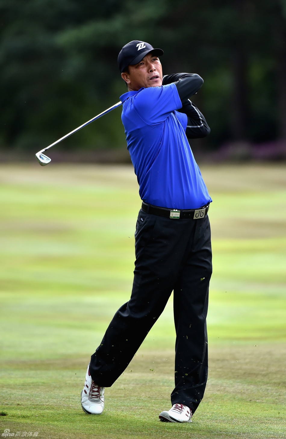 张连伟在果岭边优雅收杆，夕阳余晖为他的身影镀上一层金色光辉