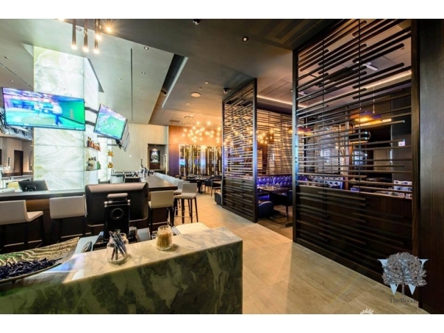 餐厅中央的现代感酒吧间，发光的石英吧台与琳琅满目的酒瓶构成社交中心。