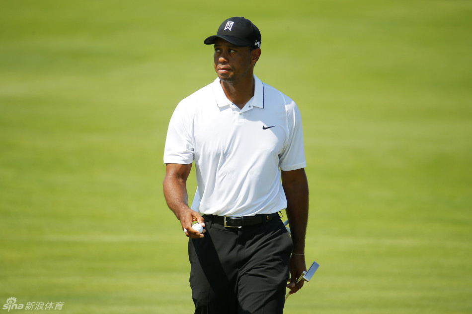 伍兹蹲在果岭边,指尖轻触草面,全神贯注地审视推杆线路的每一寸起伏