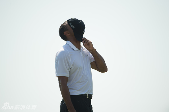 伍兹在关键推杆失误后，难以置信地双手掩面长叹，背景中观众的寂静衬托出他此刻巨大的懊恼与挫折感。