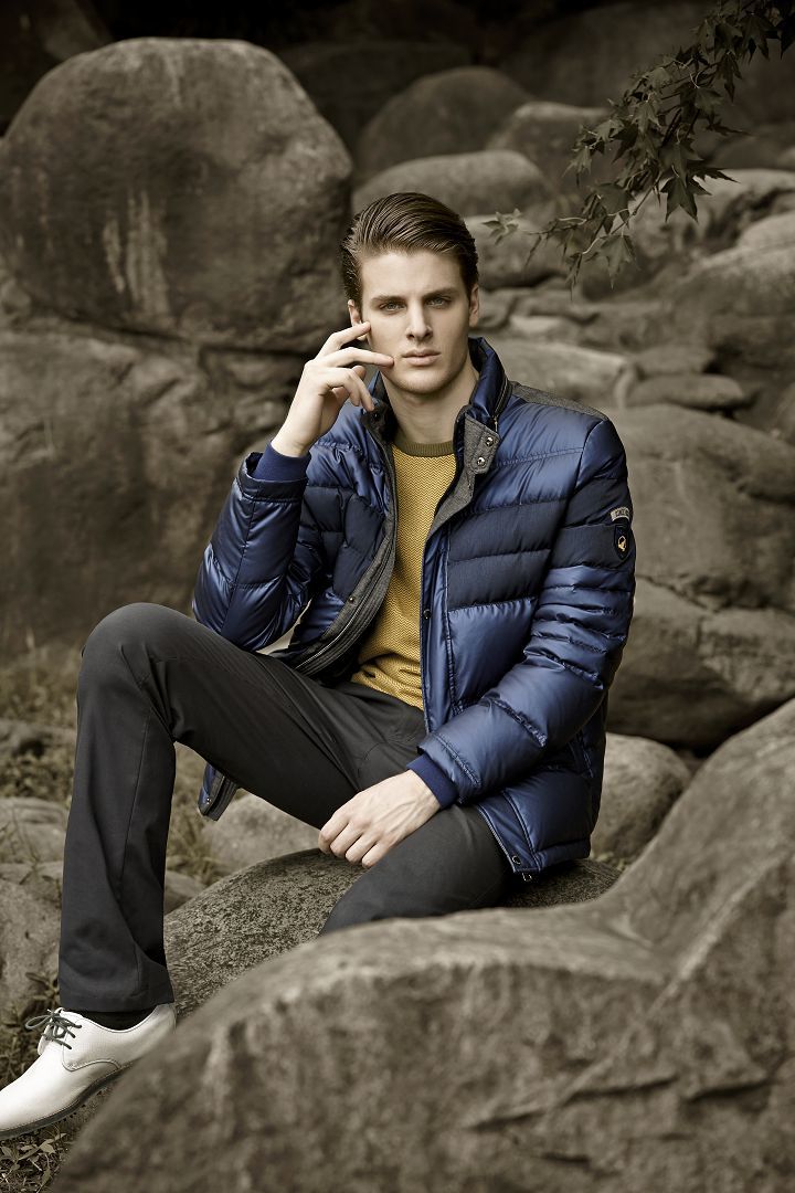 女性球员在果岭边优雅俯身观察球线，深蓝色修身长裤与驼色针织衫构成完美搭配，身后枫树红叶如火焰般燃烧