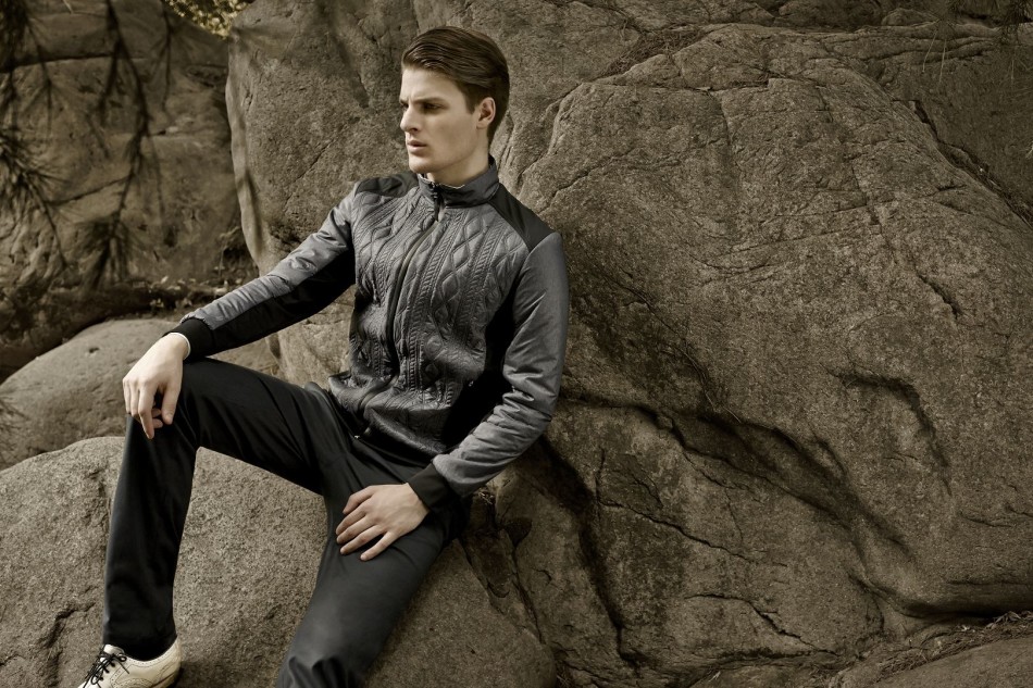 专业教练在室内教学中心示范动作，深灰色高领训练服随肌肉线条起伏，背后的落地窗外是漫天飞舞的初雪