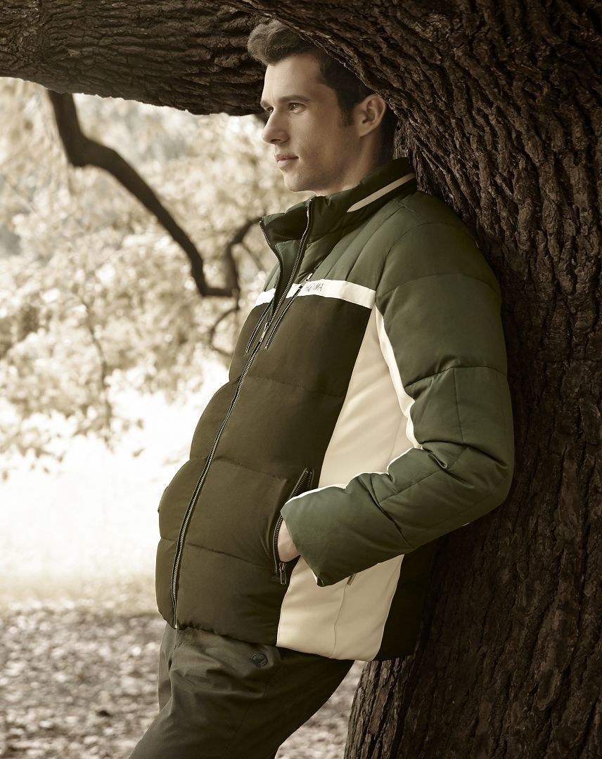 清晨薄雾笼罩的球道上，两位球手并肩而行，他们身上的石墨灰羽绒背心轻盈如晨雾，与远山轮廓融为一体