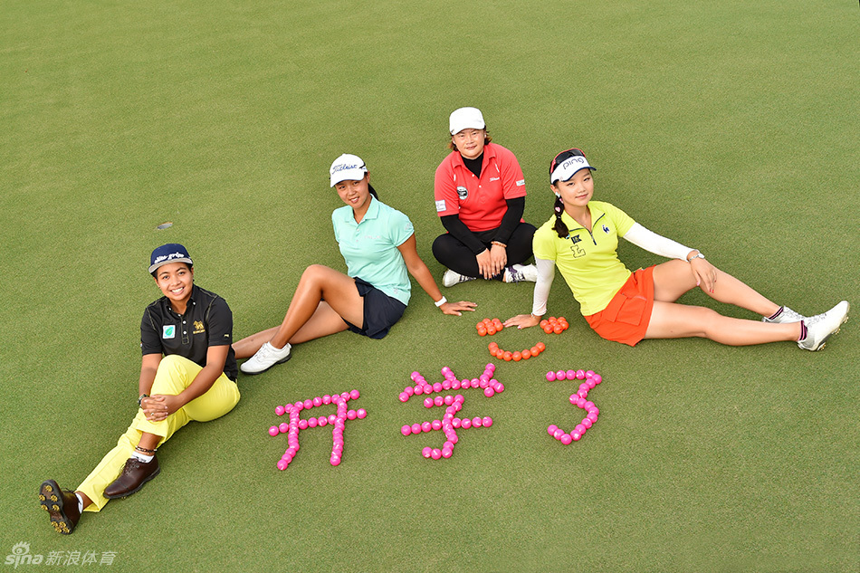 两名高尔夫球手并肩站在武汉挑战赛的发球台上,其中一位正举目远眺,评估球道情况,她们身后是郁郁葱葱的树林和准备中的球童。