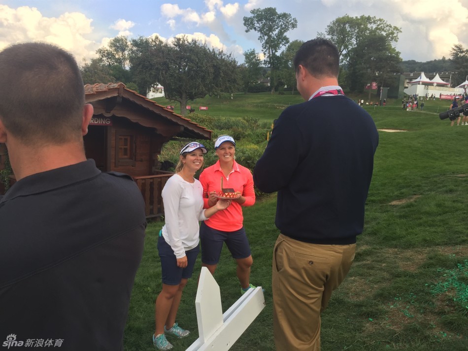 她与朋友们分享着蛋糕，欢声笑语在果岭旁回荡，构成一幅友爱的画面。