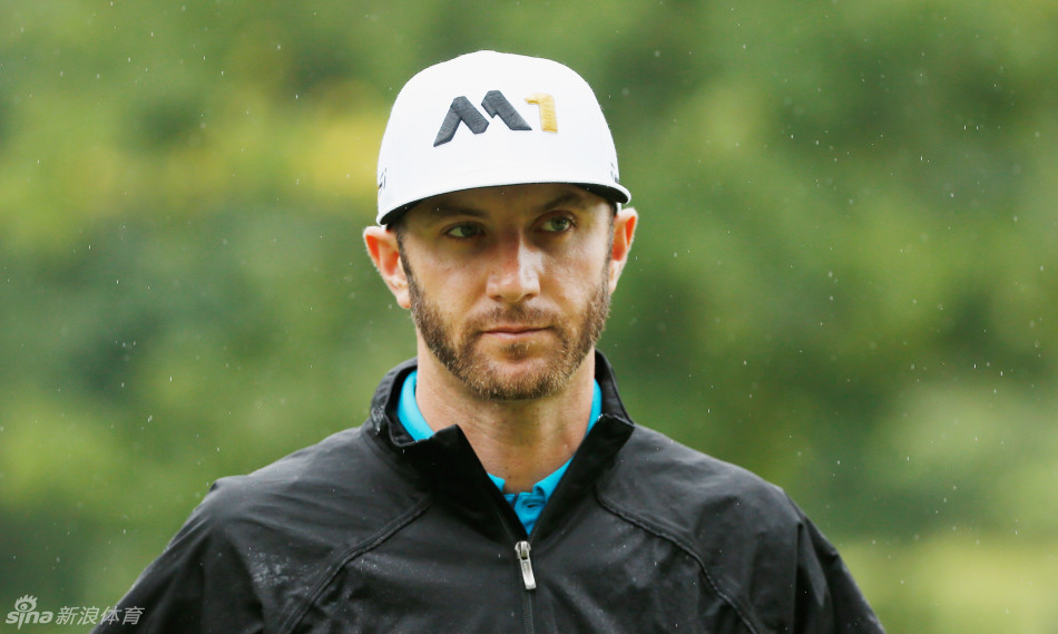 达斯汀·约翰逊在球道上准备击球，他俯身观察球位，神情专注，与身后广阔的球场构成一幅宁静而有力的画面。