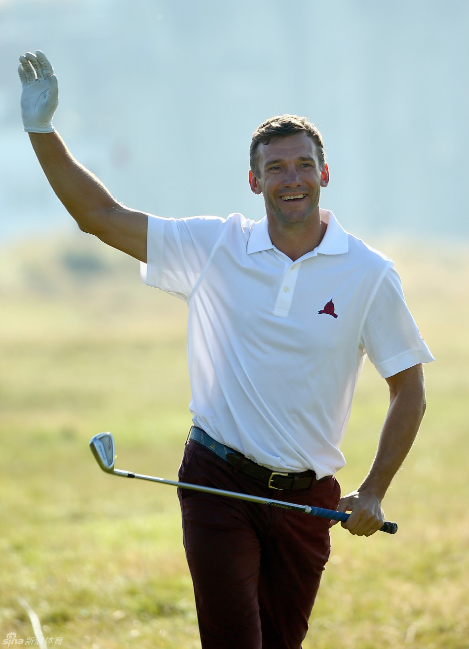 著名影星休格兰特手持高尔夫球杆，在球场边露出标志性的腼腆微笑