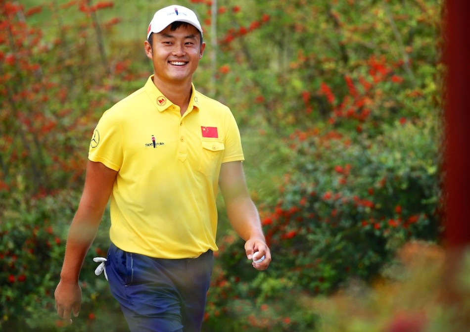 冈恩在玉龙湾球场标志性的水障碍旁自信攻果岭，水面倒映着蓝天与山影