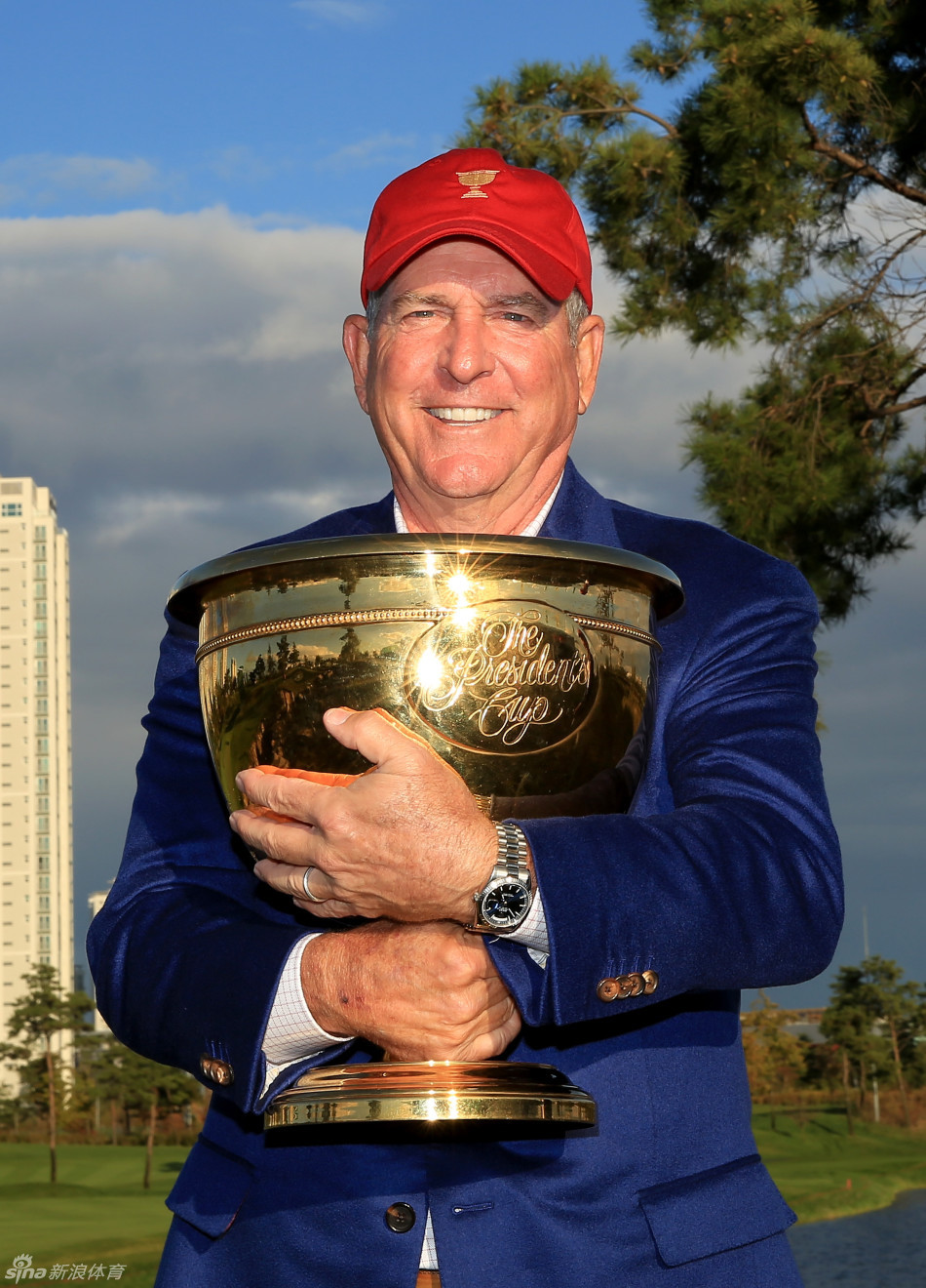 队长杰伊·哈斯亲手将金光闪闪的总统杯奖杯递给儿子比尔·哈斯，父子二人笑容满面，象征着荣耀的传承与共享