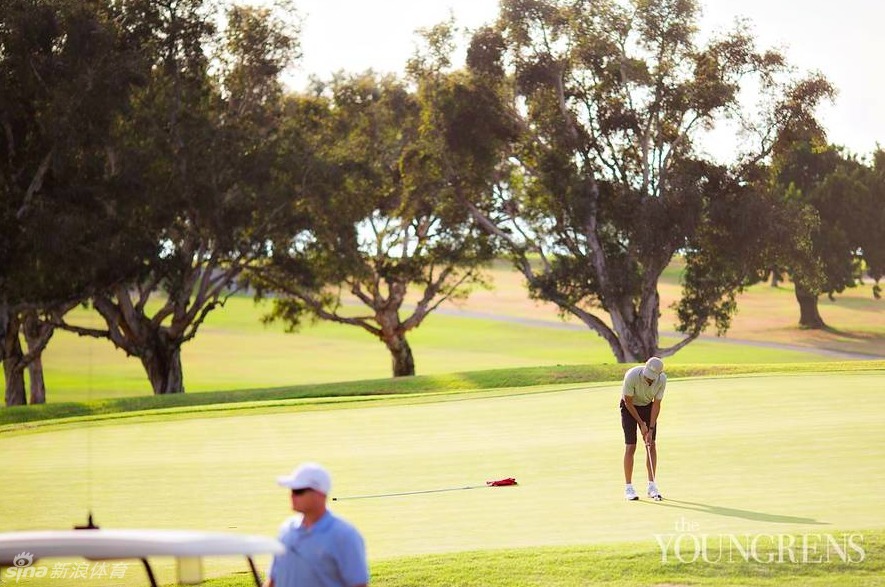 总统在随行人员的陪同下漫步于球场,身形放松,整个场景沐浴在柔和的午后阳光下,显得宁静而惬意。