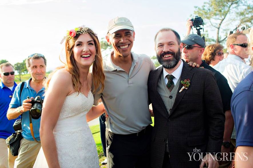 奥巴马面带标志性灿烂笑容,与新郎握手交谈,新郎同样笑得合不拢嘴,背景是开阔的高尔夫球场绿茵。