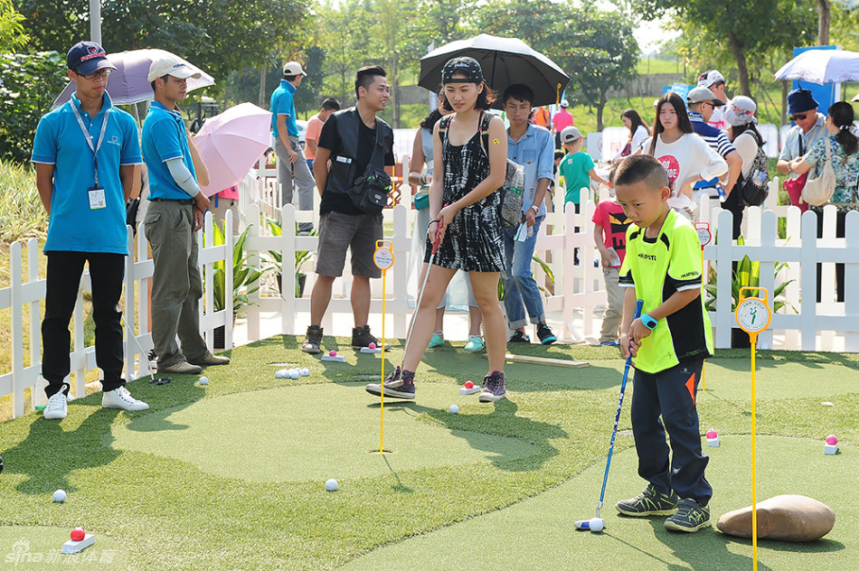一个小男孩在专业教练指导下认真练习高尔夫挥杆动作,背景是绿意盎然的练习果岭