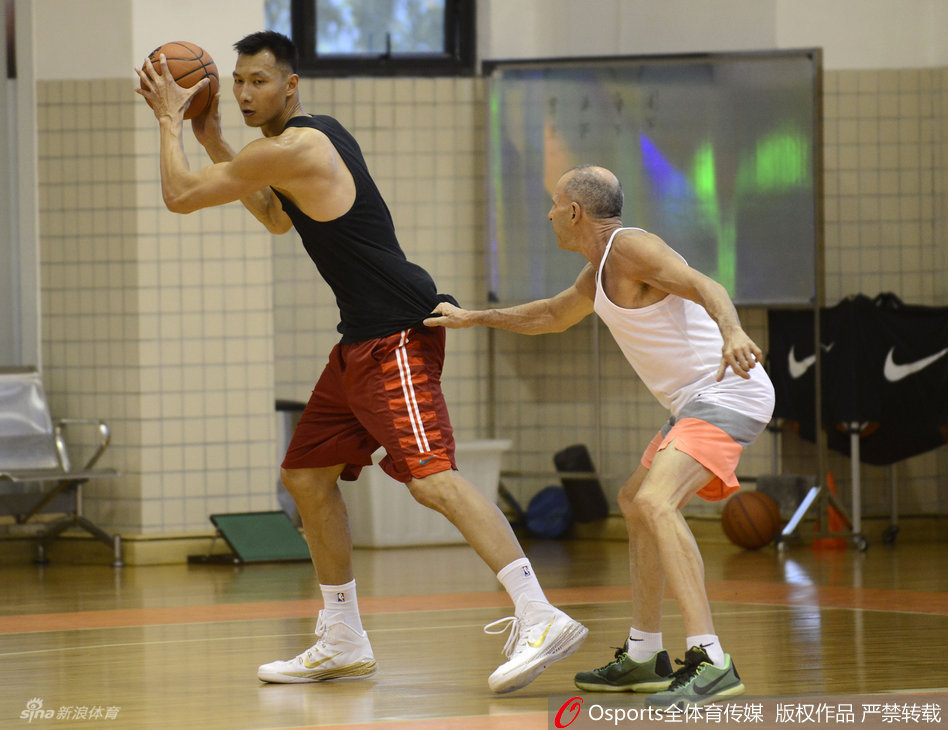 易建联在训练馆中全神贯注，双手稳稳持球，眼神犀利地审视着篮筐，仿佛即将面对的不仅是训练，而是内线强悍的对手。