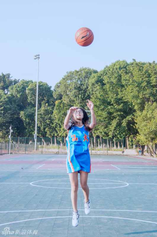 她双手抱球置于头顶，眼神专注地瞄准篮筐，准备投篮的姿势在球场背景下显得既专业又俏皮。