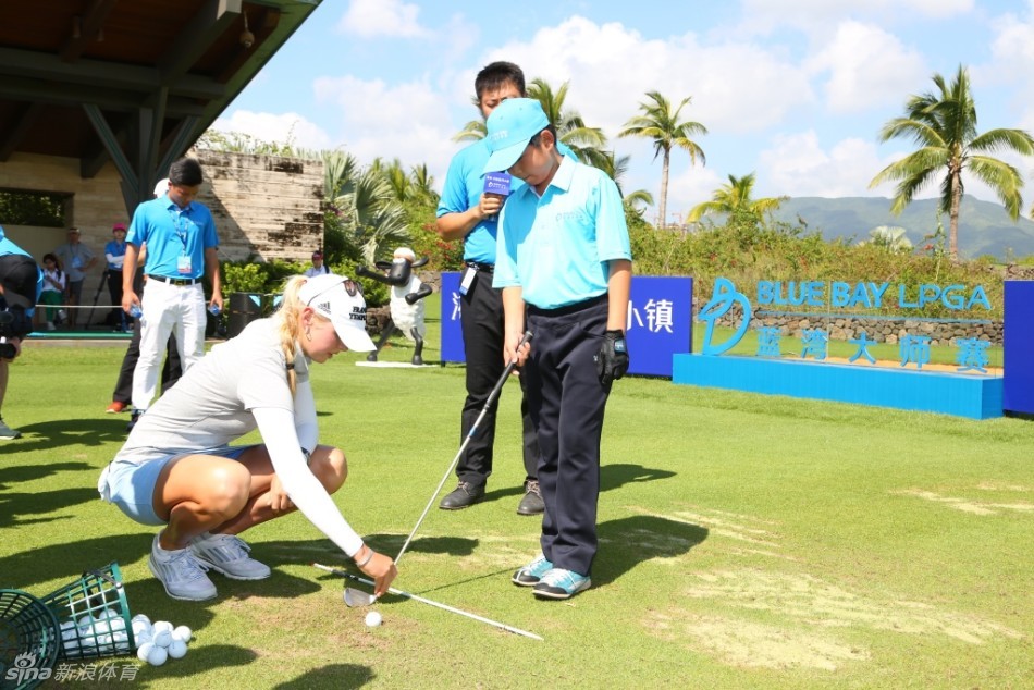 科达与一群青少年球员并肩行走在球道上，边走边亲切交流，海风吹拂着他们的衣角，画面温馨如师亦友。