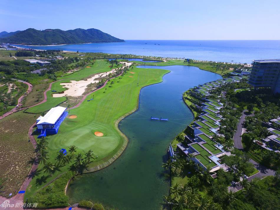 造型独特的沙坑如艺术品般散落在果岭前方，在阳光下闪耀着金色光芒，与后方深绿色的果岭和更远处的湛蓝海面形成绝妙的三重奏。