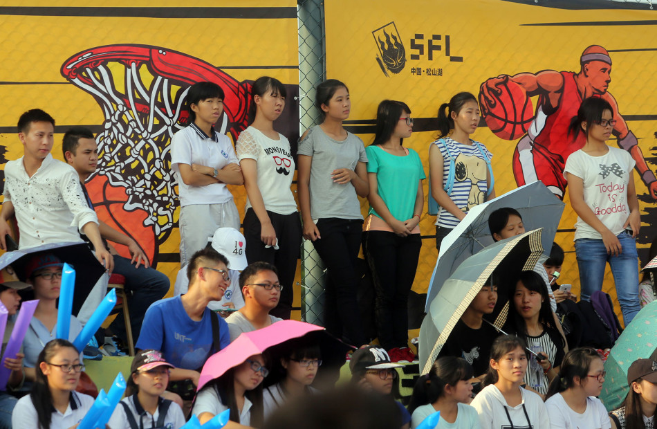 场边的观众席座无虚席，几位美女球迷也被激烈的比赛吸引，目不转睛地关注着场上局势。