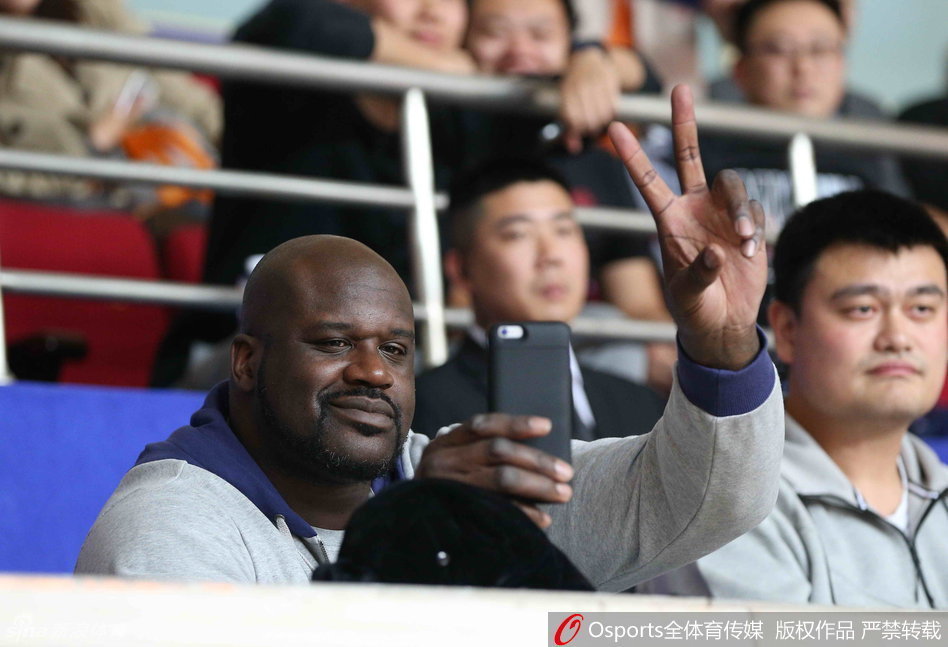 奥尼尔坐在姚明身旁，搞怪地对着镜头比出‘二’的手势，身边的姚明则是一脸宠溺的微笑，两大巨人同框的画面让场边瞬间变成了欢乐的海洋。