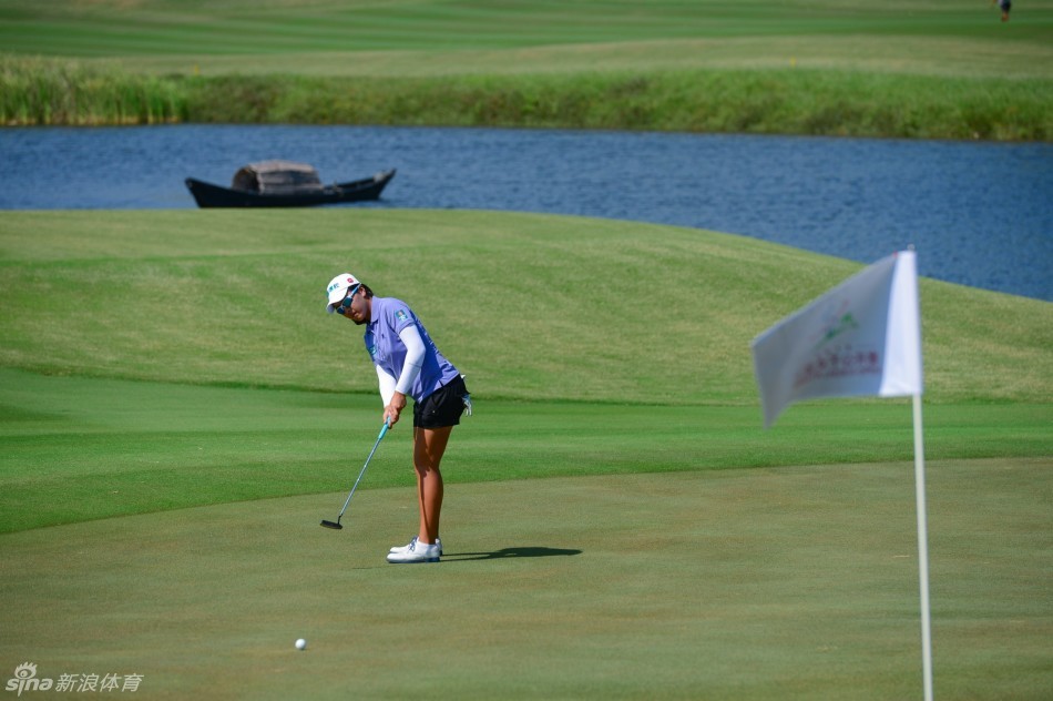 一位女球员正全神贯注地在练习果岭上进行推杆,晨曦的光晕勾勒出她专注的侧影,球杆与球之间仿佛存在着某种静谧的对话。