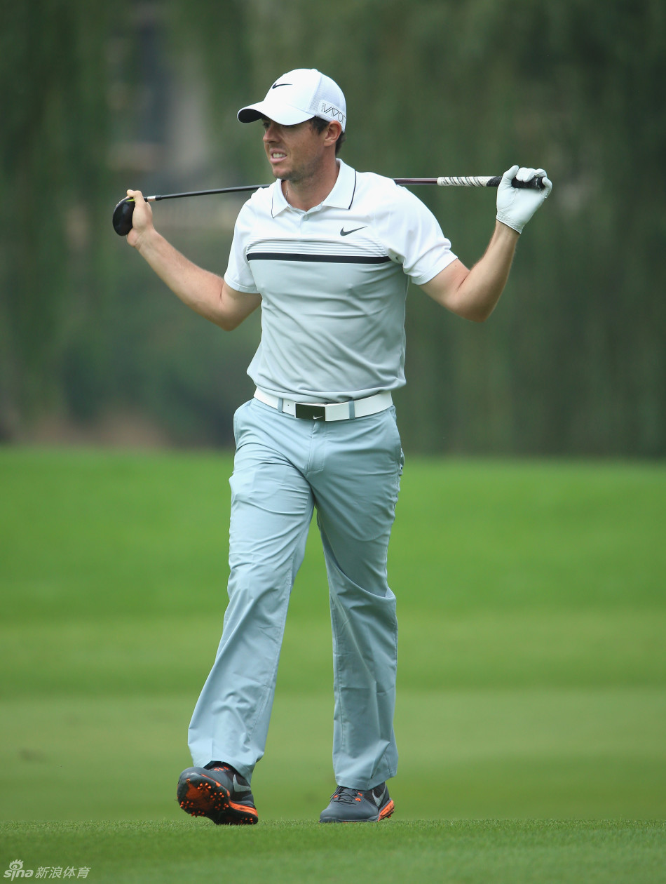 麦克罗伊在果岭边凝神准备切球，神情专注，评估着球与洞杯间的每一寸草皮