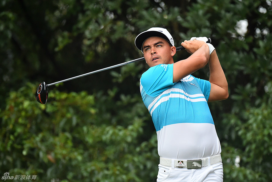 球手在临海的果岭上观察推杆线路，远处海天一色的景象美不胜收。