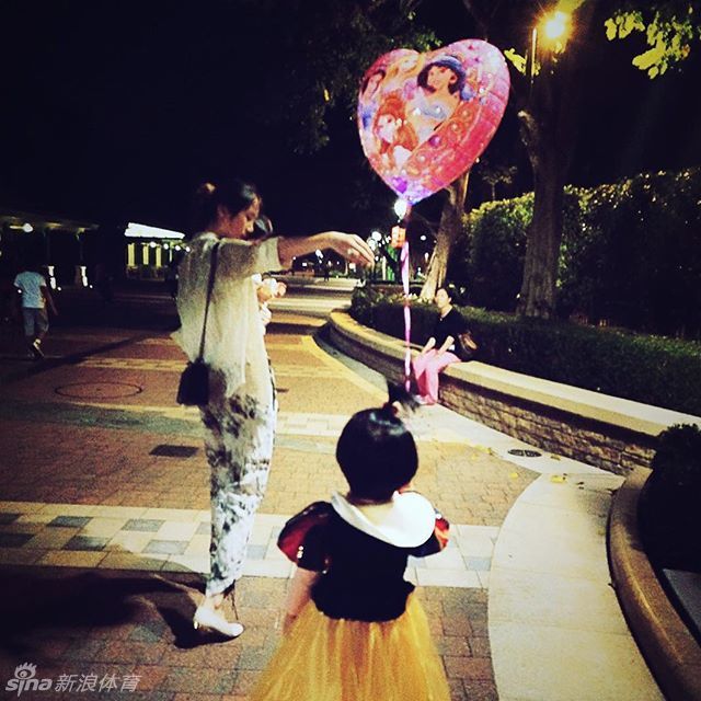 陈露蹲下身子，视线与女儿平齐，耐心地给她讲解着什么。这个小小的动作充满了尊重与平等，母爱的光辉在这一刻比周围的童话布景更加耀眼动人。