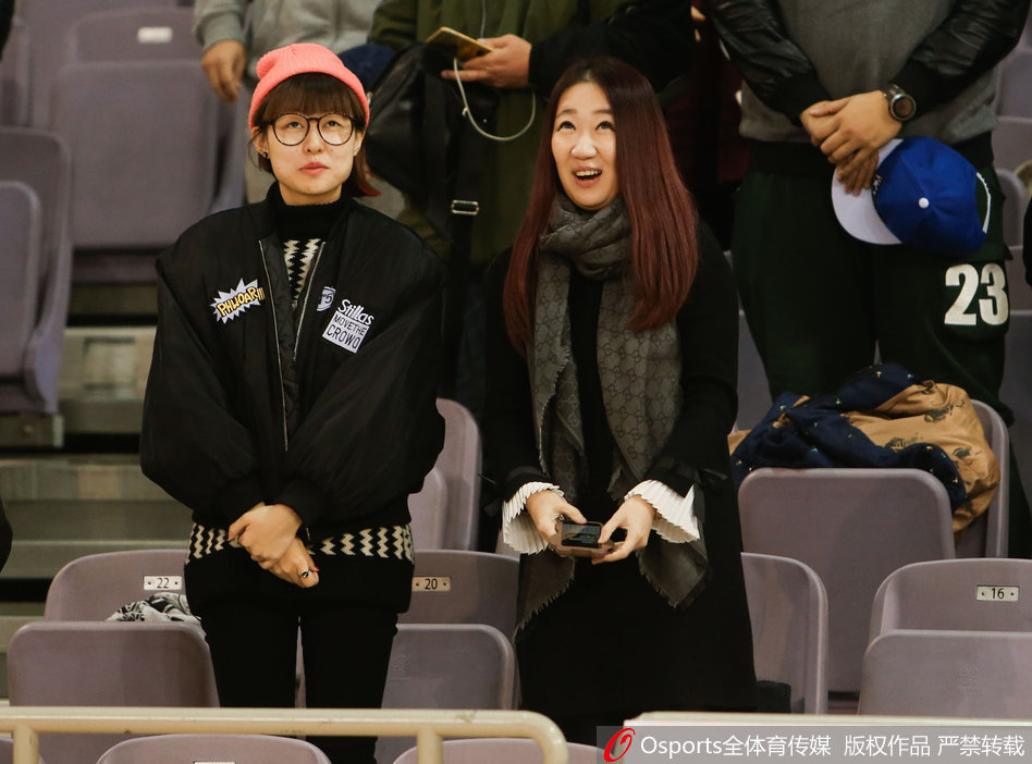 女球迷捂嘴浅笑，羞涩神情被大屏幕捕捉，眼睛弯成两道月牙