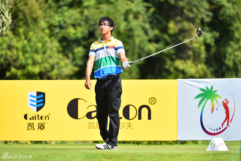 韩国选手孙俊业在海南公开赛果岭边专注凝神，山风吹动了他的衣角与草叶，他正冷静研判下一杆的路线与风的影响