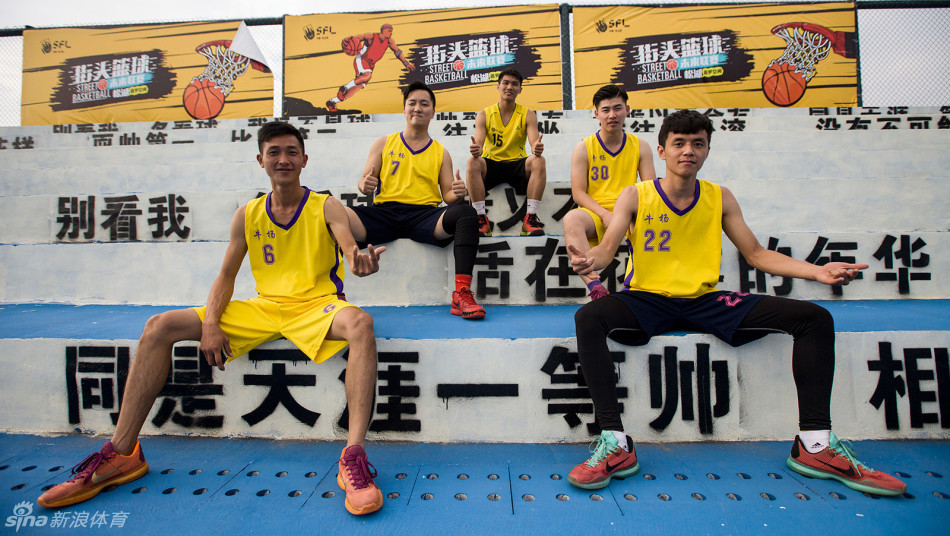 球队LIKE队合影时队员们摆出创意手势，脸上洋溢着青春的笑容，背景是充满涂鸦的训练室墙壁