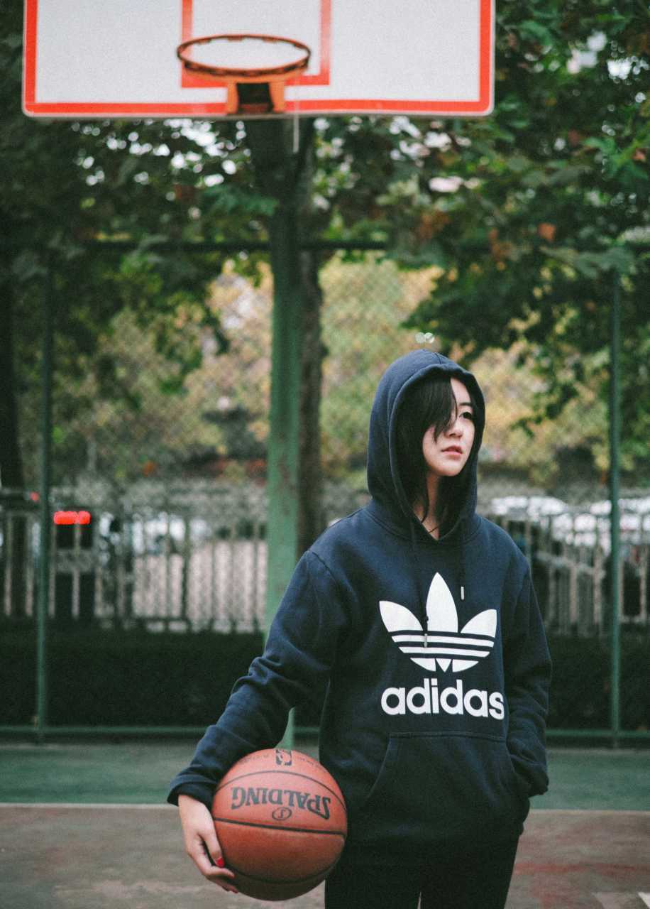 篮球女孩用球衣擦拭汗水，头发微微凌乱，但脸上的笑容比阳光还要耀眼夺目