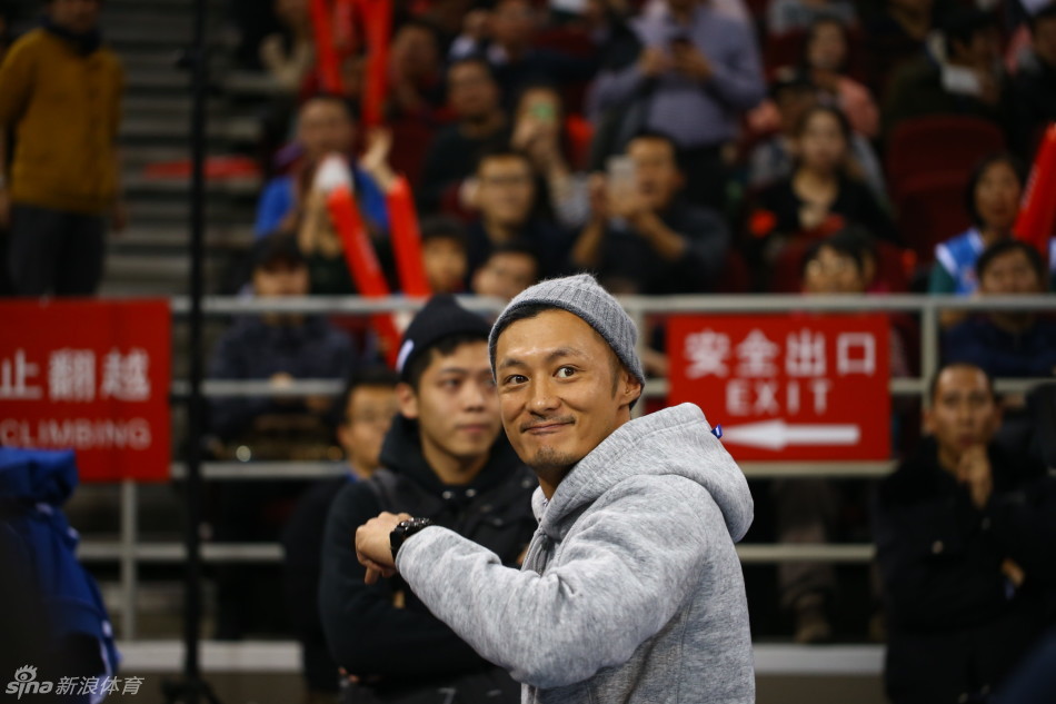 余文乐与好友麦克隋并肩而坐，麦克隋手指场内似乎正在分析战术，余文乐则侧耳倾听，两人表情认真，仿佛在进行一场专业的球赛解说。