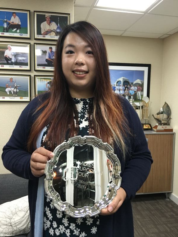 冯珊珊手捧金光闪闪的女子欧巡赛奖金王奖盘，与象征赛季总奖金榜第一的巨大支票模型合影，笑容中充满自豪。