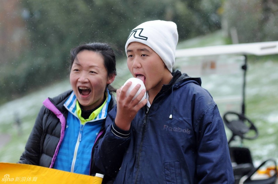 小球员好奇地捧起一捧白雪，舌尖轻触，品尝着春城冬日这难得的馈赠