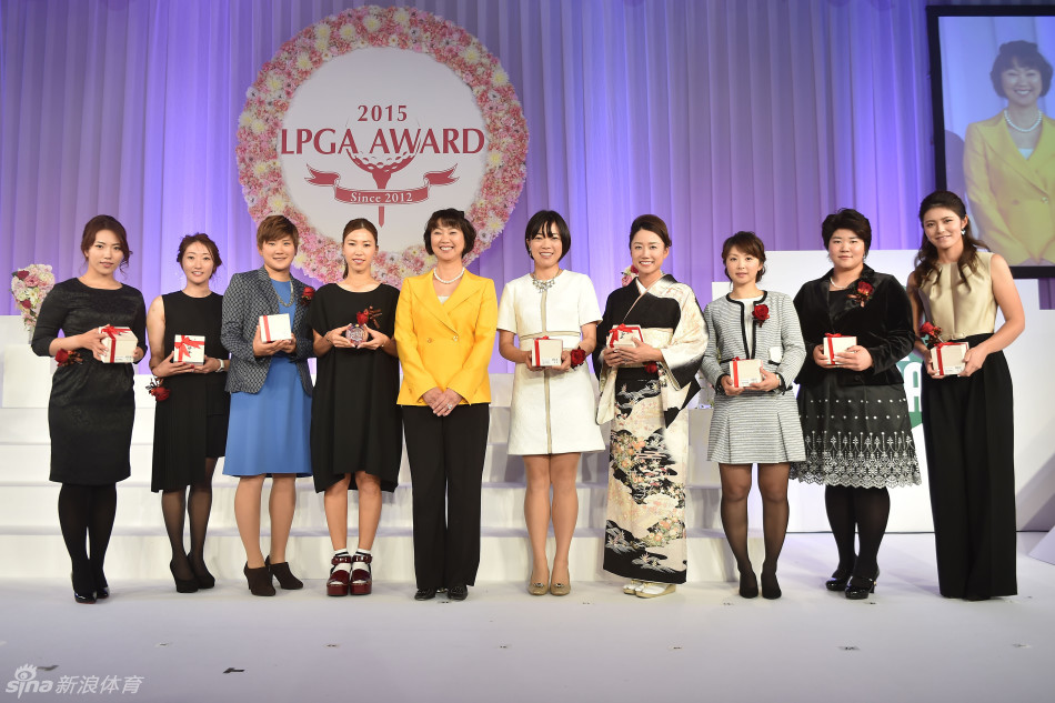 渡边彩香在领奖台上接受年度最佳杆数奖，与颁奖嘉宾握手致意，背景是熠熠生辉的赛事标志