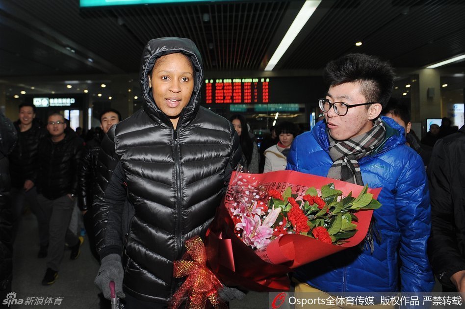 玛雅·摩尔微笑着拿出手机，与一位激动的中年男球迷进行自拍合影，身后的其他球迷也纷纷举起手机记录这追星时刻。