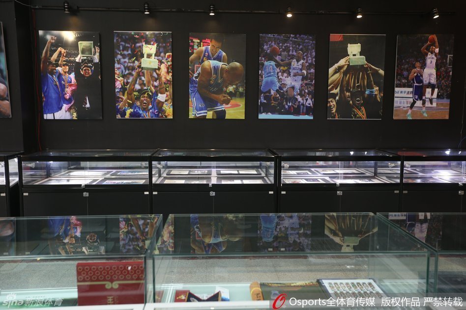 在陈列着三座CBA总冠军奖杯的展柜前，马布里深情凝望。这三座金灿灿的奖杯，不仅是他个人职业生涯的巅峰，更是他与首钢兄弟们并肩作战、征服联盟的最好证明。