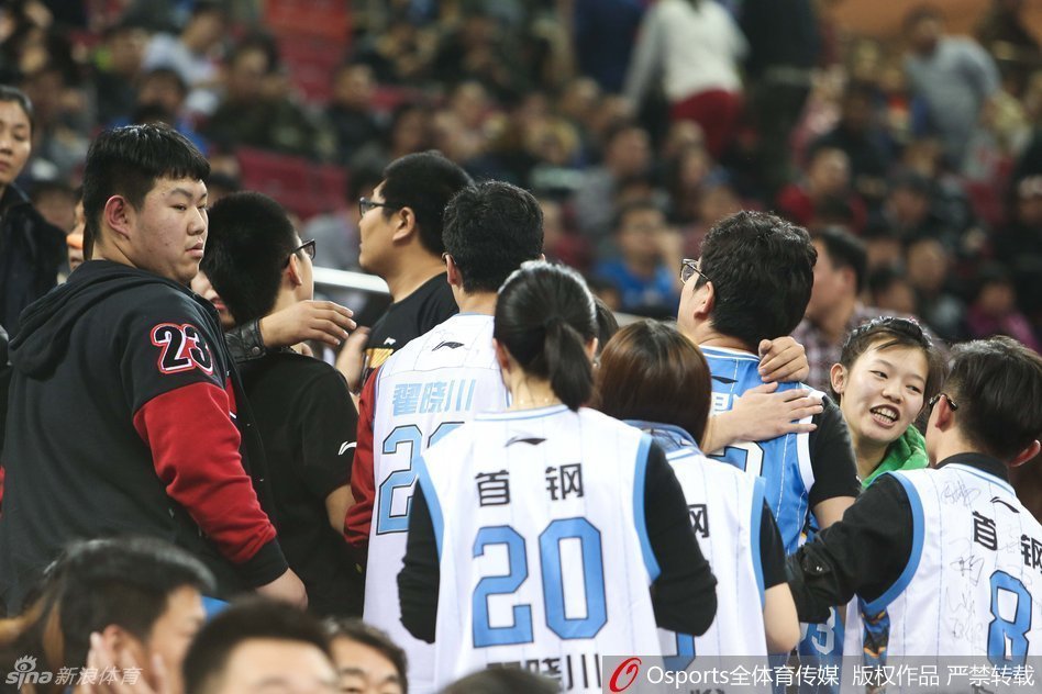 在一片混乱的看台上，几名安保人员正在耐心劝导一名情绪激动的球迷，而远处仍有球迷在争论，整个区域的气氛充满了紧张和不安。