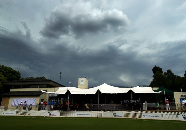 黑云压城，球场天气骤变，远处的树影在狂风中摇曳，预示着又一场雷暴即将打断激烈的比赛。