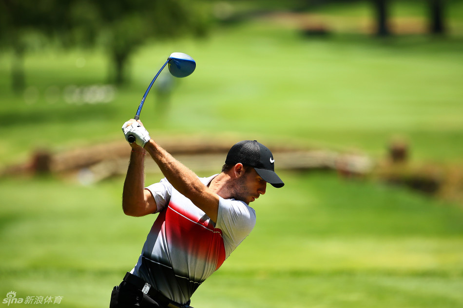 一位球员身着亮眼宝石蓝高尔夫球衫在绿茵场上潇洒行走,色彩对比鲜明充满活力