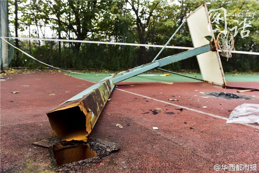 发生断裂的篮球架，根部完全与地面脱离，粗大的金属管柱扭曲变形，显示出当时承受的巨大冲击力，也暴露出设施维护的严重缺失。
