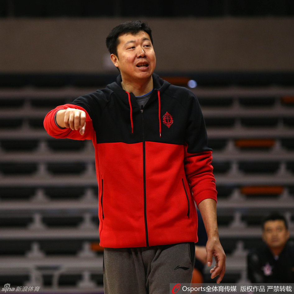 身着黑色训练服的王治郅双手抱胸，目光如炬地盯着场上球员的训练，嘴角挂着他标志性的微笑，仿佛在思考着如何将这些年轻人的天赋捏合成一个整体。