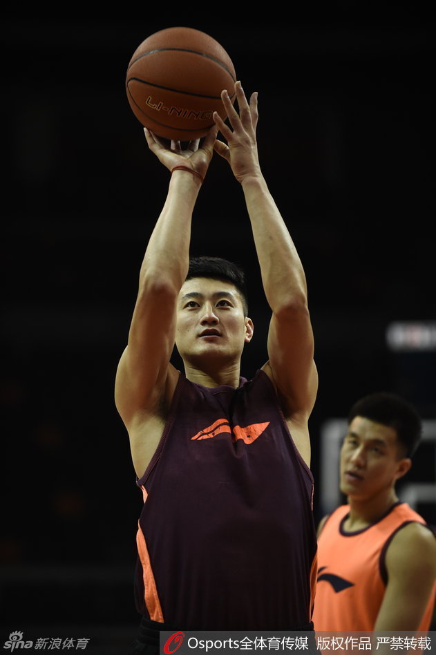 山西队的段江鹏在训练中认真练习投篮，身旁的篮球架下，队友们正在等待下一轮的投篮训练。