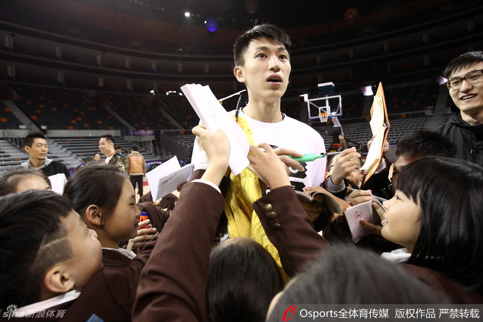 上海队后卫刘晓宇俯身为热情的小球迷签名，脸上洋溢着温暖的笑容，场面十分温馨。