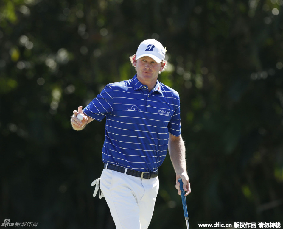 美国名将布兰德·斯内德克尔正进行标志性的‘砸打式’推杆，手腕上翘，目光如炬，专注于将力量在触球瞬间完全释放。