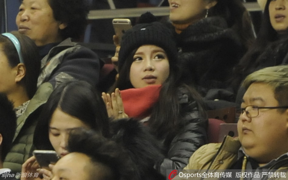 王俪婷举起手机，试图记录下郭艾伦在场上的精彩瞬间，她的脸上写满了对男友的崇拜与爱意，仿佛要将这些拼搏的时刻永久珍藏。