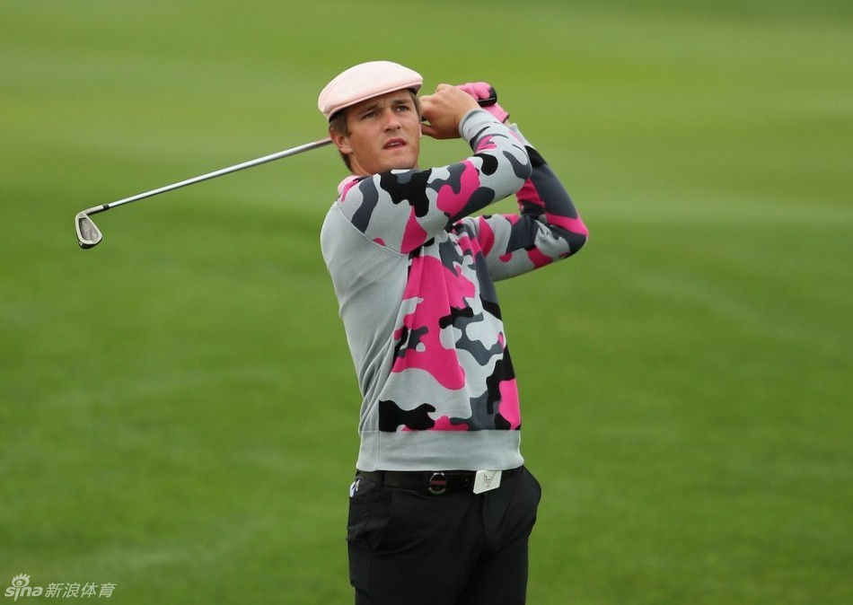 首轮并列领先者路易·乌修仁与他的球童在果岭边认真研读推杆线路，进行战术商讨。